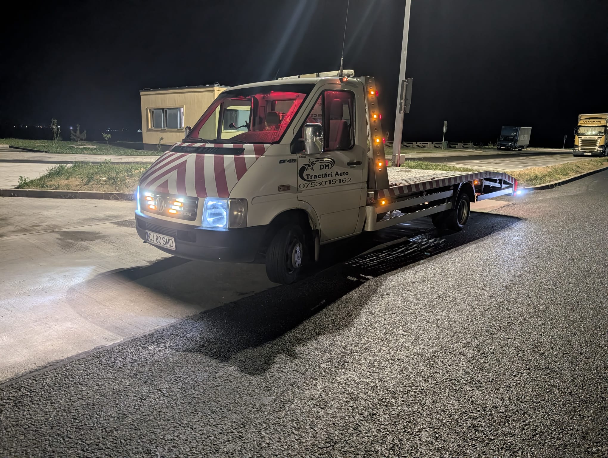 Platformă auto iluminată pe un drum, noaptea